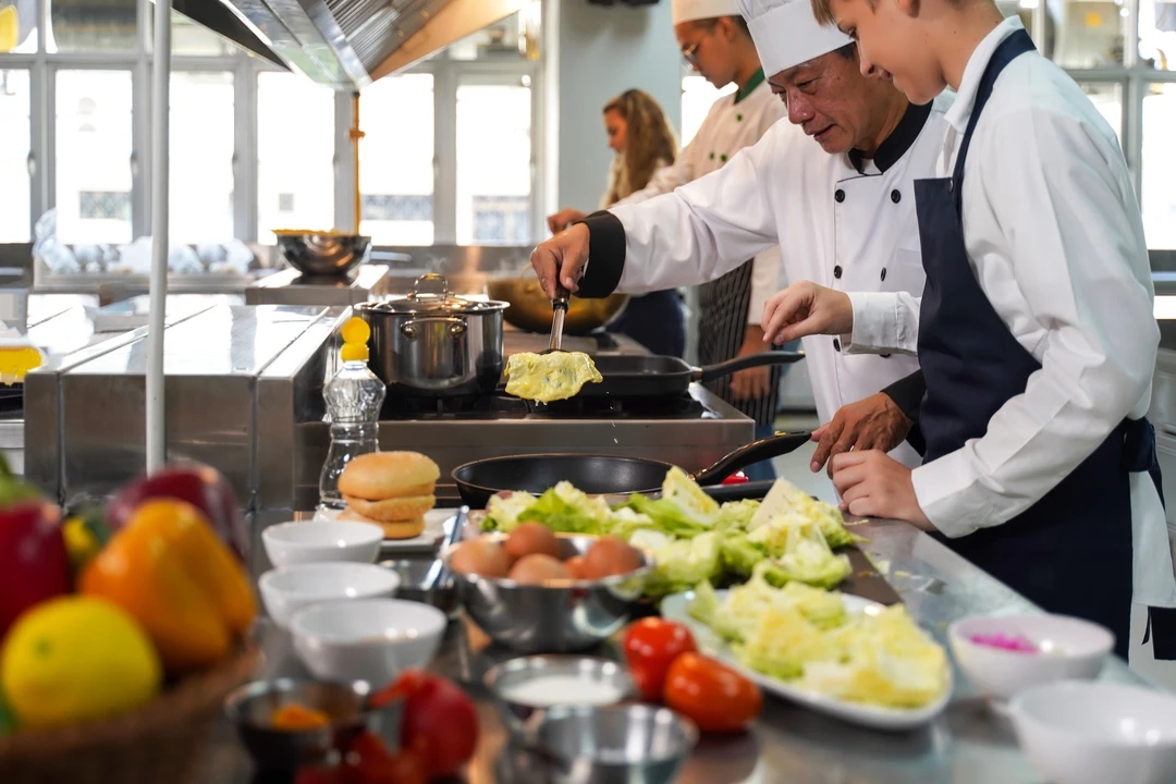 Chefs work together in a modern kitchen, preparing fresh ingredients like lettuce, tomatoes, and eggs for a meal.